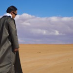 یک مرد  اسرارآمیز با شنل چشمگیر که در صحرا قدم می زند