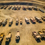 10 number of mining dump trucks located middle of the picture and left and right side is a mountains. the huge truck shovel in middle of them  and cargo and body that resembles like the robots in the Transformers movie