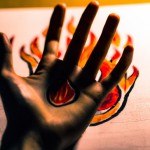 و پشت دست عکس دستی که در آن آتش است