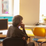 A crowded room and an old computer on the table, a window with light coming from outside, warm lighting, a 30-year-old man with white hair sitting on a chair and thinking about upgrading everything