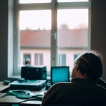 A crowded room and an old computer on the table, a window with light coming from outside, warm lighting, a 30-year-old man with white hair sitting on a chair and thinking about upgrading everything
