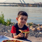بچه در حال خوردن پیتزا و خیار و زیتوت در کنار رودخانه دز شهر دزفول