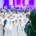 تصویر یک دختر محجبه ی عکاس که در یک جلسه بزرگ در حال عکاسی است