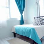 یک تخت خواب در سمت راستیک پنجره رو به رو با رنگ آبی