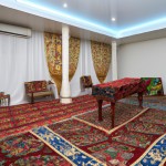اتاق پذیرایی سنتی ، مدل ایرانی، با پرده توری چیندار، فرش ایرانی پشتی‌های مخملی گل‌های شمعدانی