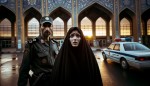 یک زن ایرانی با چادر مشکی  و صورتی کبود و آشفته صبح زود روبه روی اداره پلیس ایستاده و کنار اداره پلیس یک مامور ایرانی در حال نگهبانی است