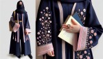 عکس یه دختر دبیرستانی ایرانی که مانتو و شلوار و مقنعه سورمه ای پوشیده و روی مانتوش یه آستین بلند صورتی که گلای ریز سفید داره پوشیده و دست چپش یه ساعت طلایی ظریف دستشه و یه کتاب هم دستشه