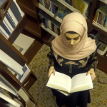دختر نوجوان محجبه و علاقمند به کتاب، در حال کتاب خواندن در کتابخانه بزرگ.