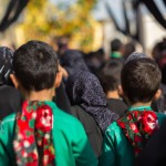 سه پسر 10 ساله ایرانی و عراقی و فلسطینی در میان عزاداران حسینی در حال حرکت به سمت حرم امام حسین در مسیر پیاده روی اربعین در میان موکب ها و پرچم های عزاداری