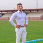 عکس فرشاد با پیراهن سفید و شلوار آبی روی چمن ورزشگاه