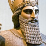 Create a full-body character depiction of Cyrus the Great, the founder of the Achaemenid Empire, dressed in traditional ancient Persian royal attire. He should wear an elaborate golden crown with intricate patterns, symbolizing his role as a king. His robe is richly decorated with vibrant colors like deep red and gold, featuring traditional Persian motifs and embroidery. Include a majestic cape draped over his shoulders. His stance is regal and confident, holding a scepter in one hand and a scro