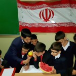 شب یلدا در مدرسه کنار بچه ها و مدیر با هندوانه و پرچم ایران
