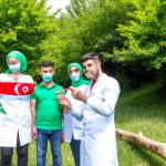 یک دندانپزشک آقا در طبیعت در حال آموزش دادن مسواک زدن ب مردمی ک جلوش نشستند هست لباس مردم ب رنگ پرچم ایران است