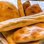 روی یک میز یک نان سنگک دو نان بربری سه نون باگت و یک نان تافتون