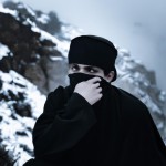 یک مجاهد مسلمان با لباس سیاه و با چفیه صورت خود را پوشانده و فقط چشمان او مشخص است،او در یک کوهستان برفی است