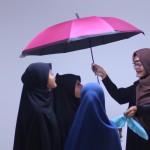 عکس یک معلم با حجاب کامل و چادر که چتر مهربانی و آموزش و پیشرفت دانش آموزانش را به دست دارد و روی سر دانش آموزانش گرفته است