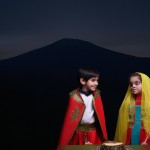 کودکان با لباس های محلی ایرانی با رنگ های مختلف دور سفره هفت سین که در کوهپایه قرار دارن و پشت سرشون کوه دماوند قرار داره