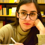 تصویر یک دختر با چهره آرام که در کتابخانه‌ای در حال درس خواندن است  دارد تلاش می‌کند فضای تصویر آرامش بخش باشد چشمان دختر سبز رنگ و موهایش خرمایی روشن باشد و عینک داشته باشد