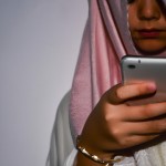 یک خانم با حجاب درحال تماشای گوشی