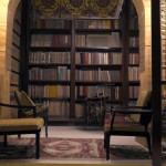 An elegant traditional library interior inspired by Persian and Islamic design, tall dark wood shelves, arched windows with geometric lattice, Persian rug, brass warm lighting, velvet armchairs, soft shadows, photorealistic. aspect_ratio 16:9