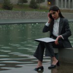 یک خانم وکیل زیبای ایرانی با لباس رسمی در خیابان نیاوران بالاشهر تهران زیر باران غمگین کنار جدول نشسته است و پرونده ای در دستش است