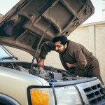 یک مرد تعمیرکار ایرانی  درحال کار در کنار یک خودرو ایرانی با کاپوت باز چهره واقعی و لباس کار