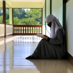 تصویر دختری با پوشش اسلامی درحال خواندن کتاب احکام در حوزه علمیه به صورت واقعی