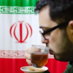 رستم با پس زمینه پرچم ایران درحال نوشیدن چای