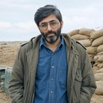 شهید سید مرتض آوینی با پیراهن آبی لی / موی کمی سپید / پیراهن تا کمر دیده شود / اورکت قدیمی کره ای زمان جنگ روی پیراهن بپوشد صورت و کله کاملا دیده شود / لبخند خیلی کم و ملیح ملیح بزند