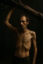 یک مرد خیلی لاغر با یک دست درخت را بلند کرده است